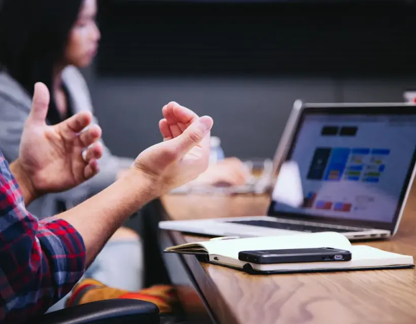 A consultant explaining a point in a meeting, a laptop open on the table