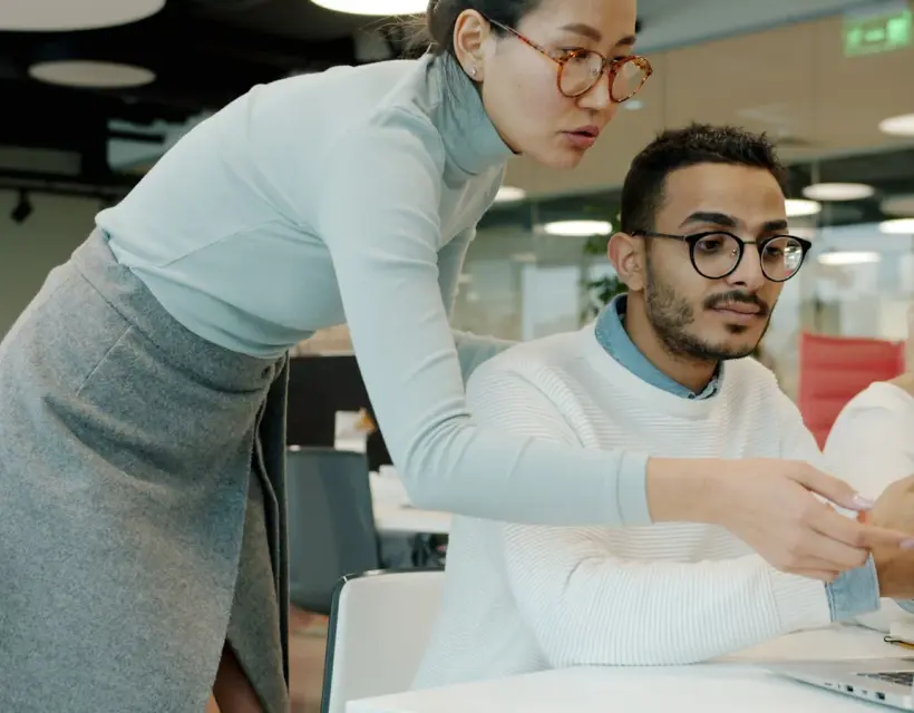 An IT specialist assisting a colleague at their workstation