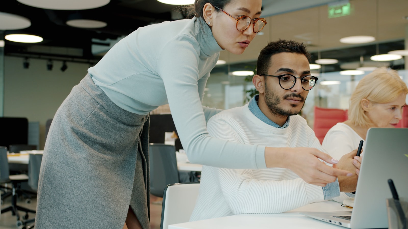 An IT specialist assisting a colleague at their workstation