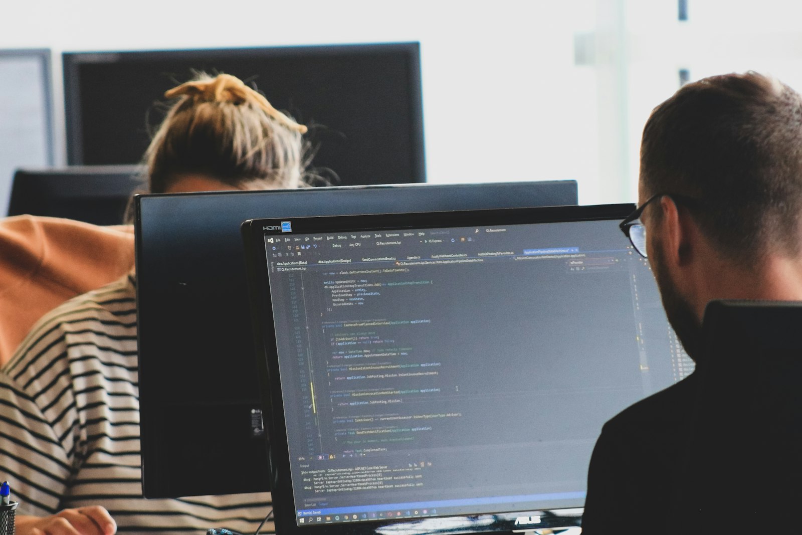 Two developers reviewing code on their screens